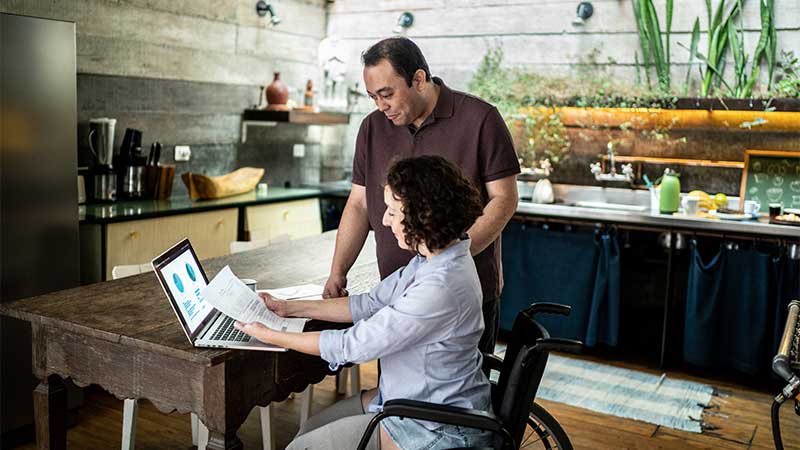 couple looking at spreadsheets on a computer in their kitchen
