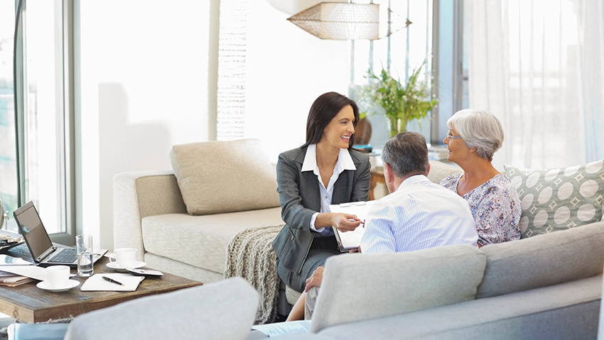 Business woman sits with a couple at their home talking about finances