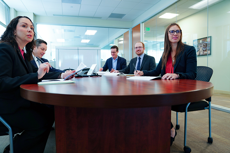 Team meeting at a large wooden table with glass walls.