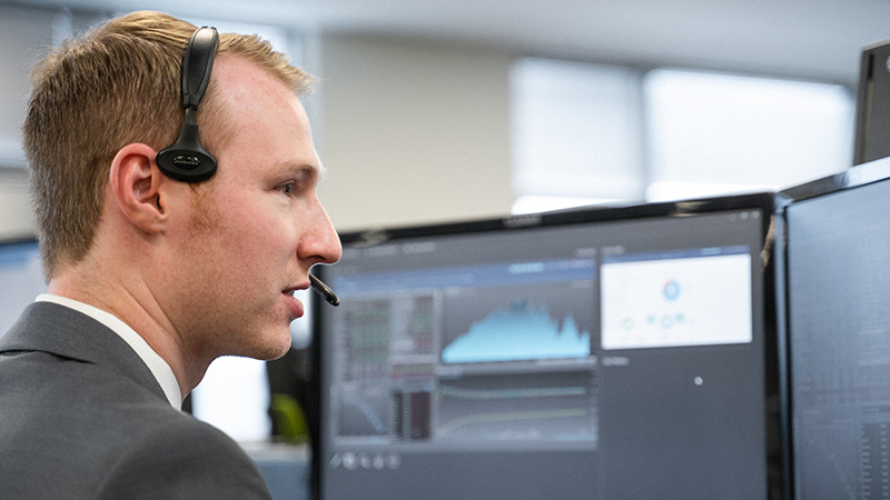 Business man at his desk while on the phone and looking at a computer