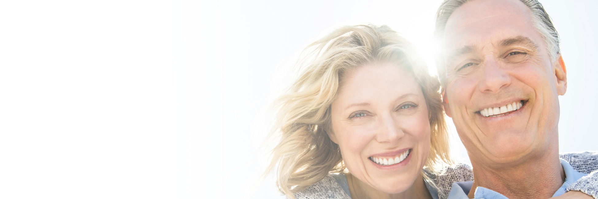 Woman with arm around man and the sun is behind them