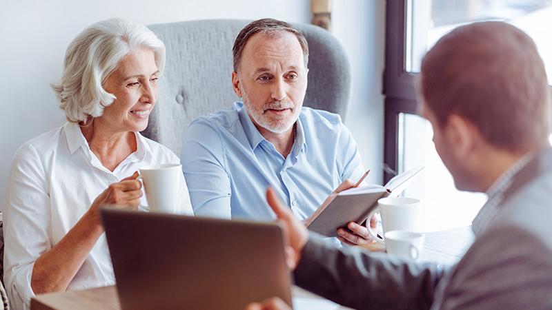 couple with a financial advisor reviewing investments in their retirement account for a professional investment portfolio management recommendation 
