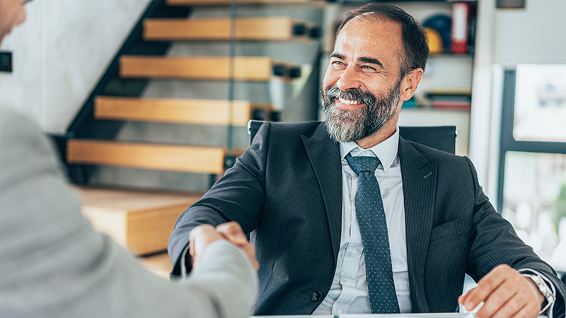 Man shakes hands with another man off camera