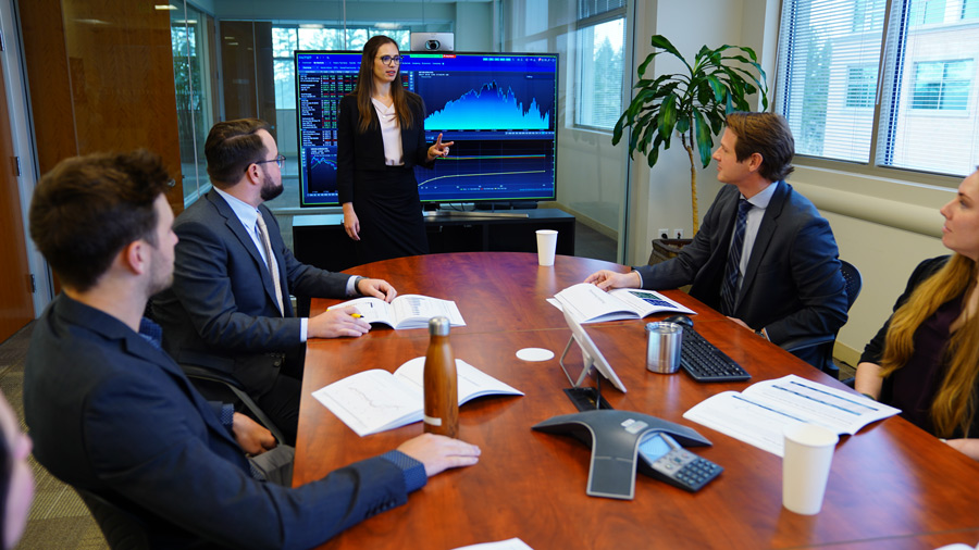 Team meeting with graph on a TV behind the speaker