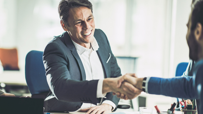 A man smiling and shaking hands with a business partner