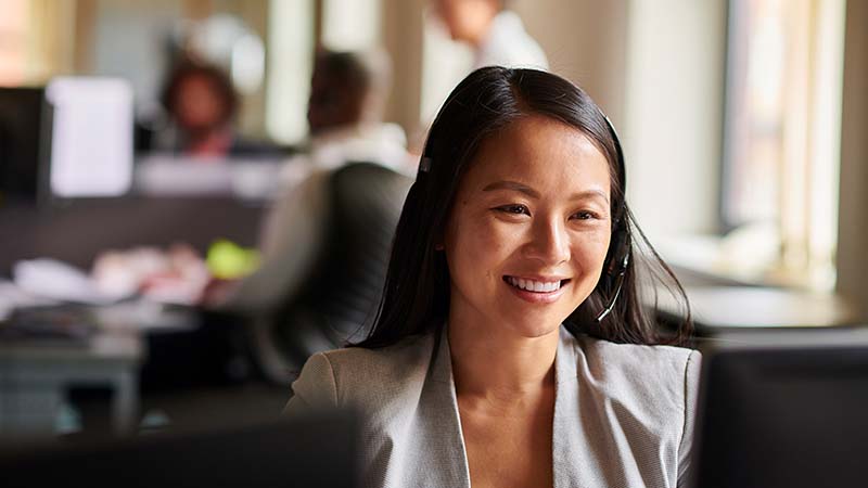 Businesswoman at a computer talks to someone over a headset
