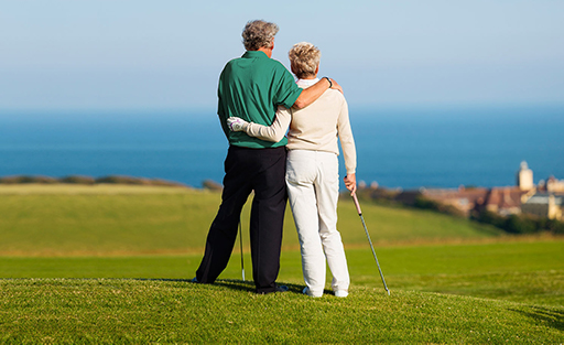 Couple with arms around eachother playing golf over looking the ocean