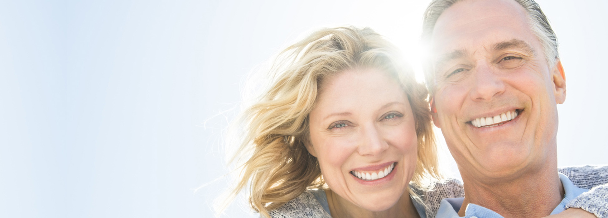 Woman with arm around man and the sun is behind them