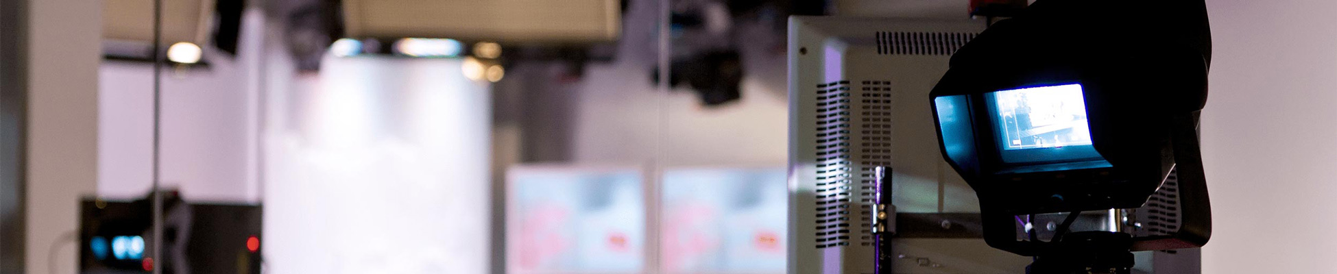 Viewing from behind a camera, four people sit at a table on a television broadcast