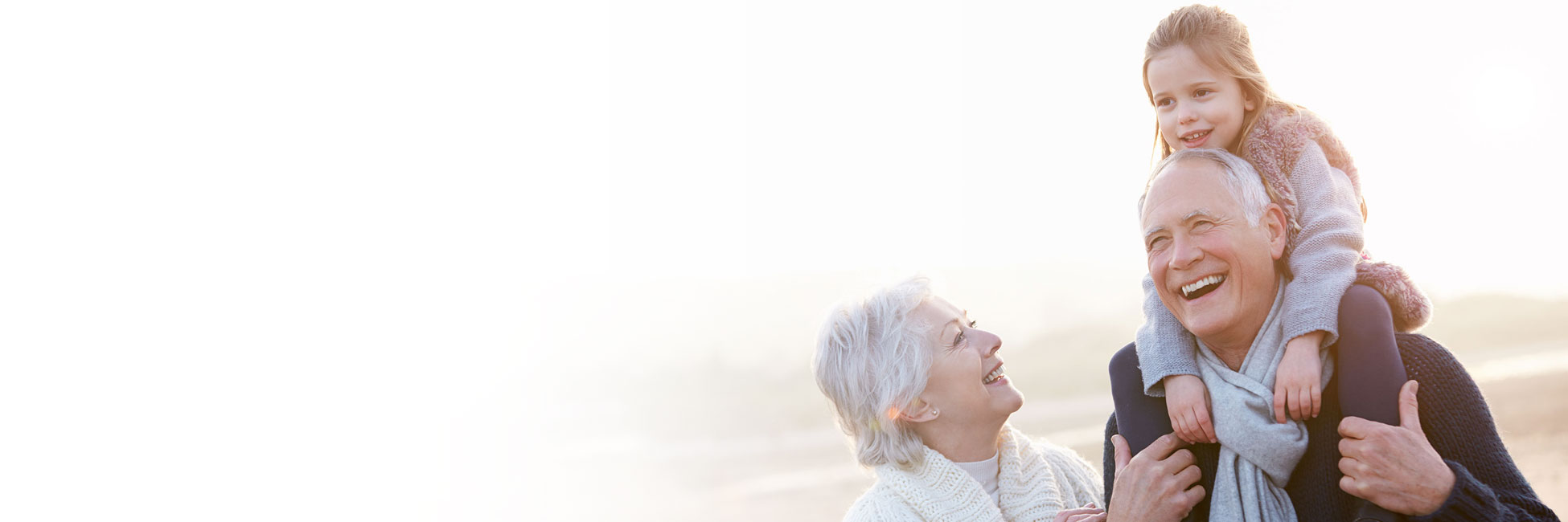 Couple with Granddaughter riding on Grandpa's back walking on the beach