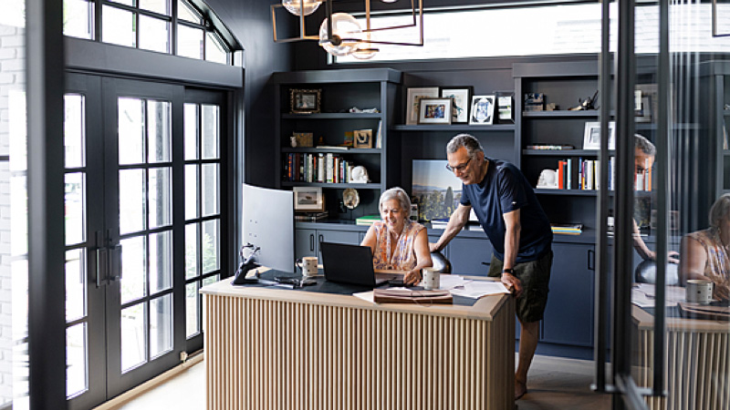 A couple collaborating while using a laptop at a desk