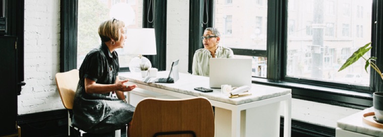 Two women discuss finances while sitting at a desk
