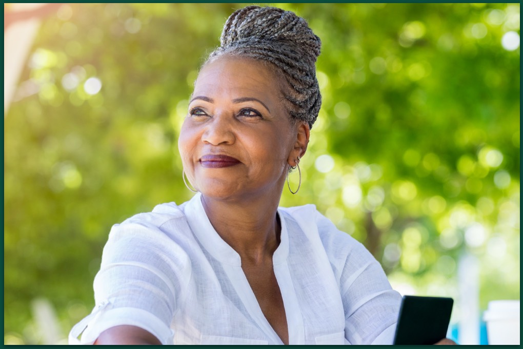 Older person holds phone while looking at the sky at a park