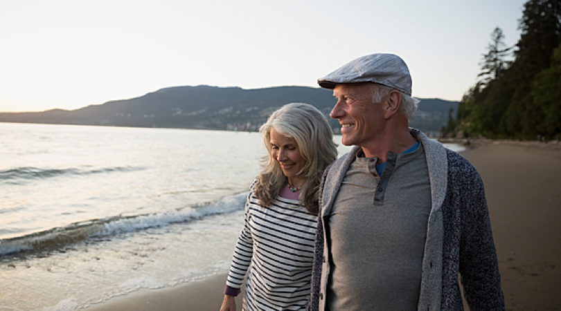 Two people walking together close on the beach