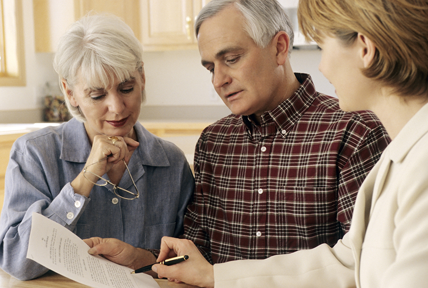 older couple with a business professional looking at paperwork