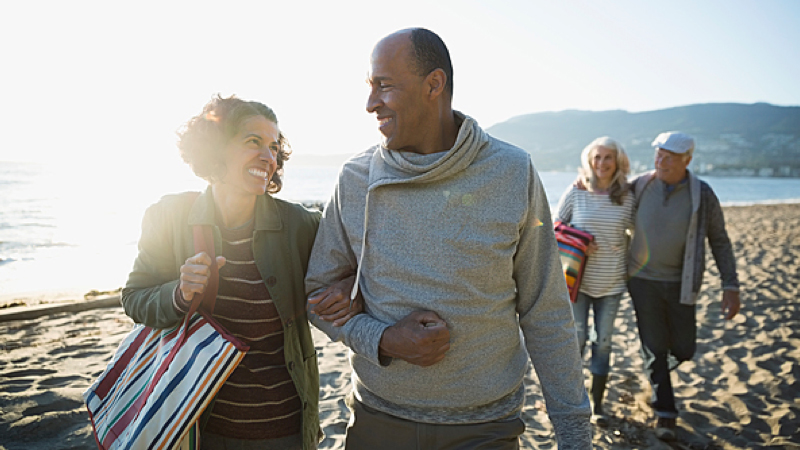 Two couples walking on the beach linking arms
