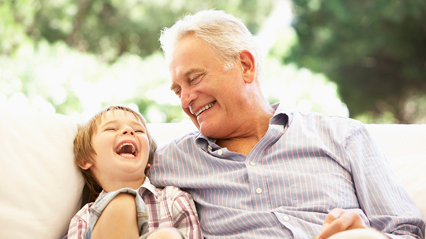 Grandpa laughing with grandson on the couch