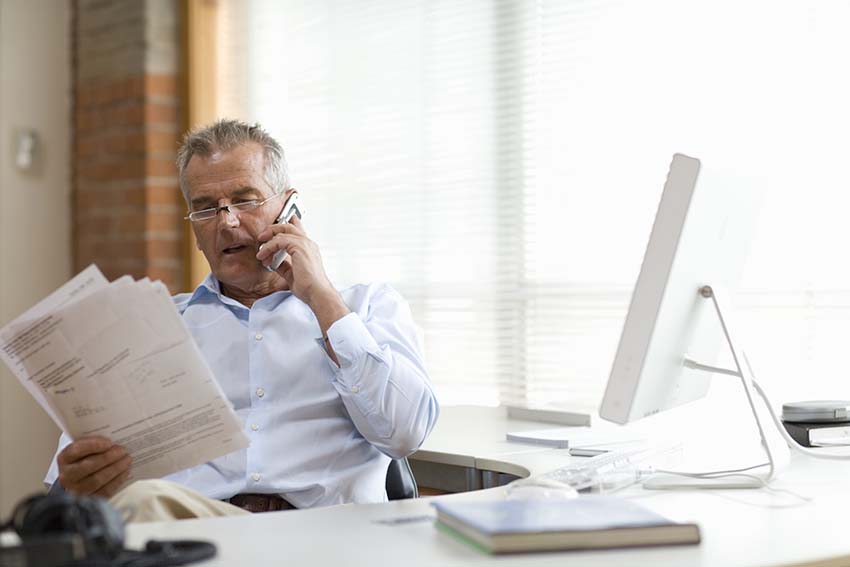 business professional talking on the phone while looking at paperwork