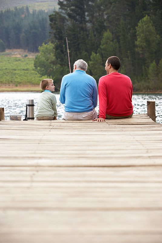 Grandpa, Son and Grandson sit at the end of a dock fishing