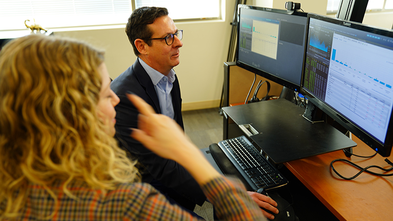 business professional looking at charts on the computer with coworker