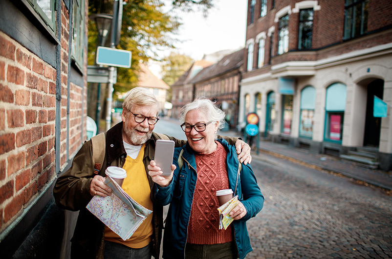 Man and woman looking at a cell phone walking along a European coble stone street