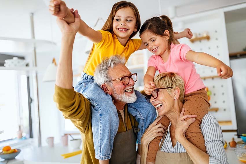 Two people smiling with two smiling children on their shoulders