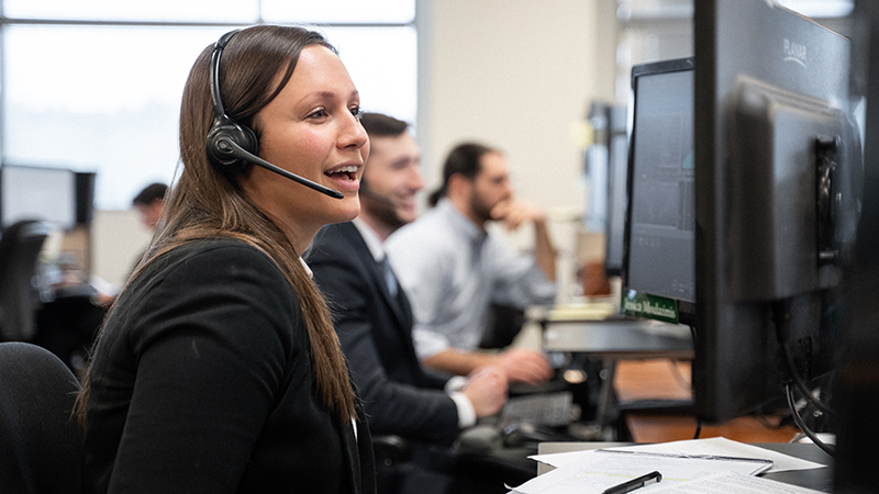 Businesswoman at a computer talks to someone over a headset