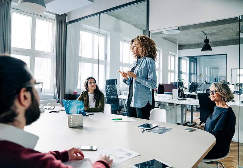Business leader standing and speaking with group around a table
