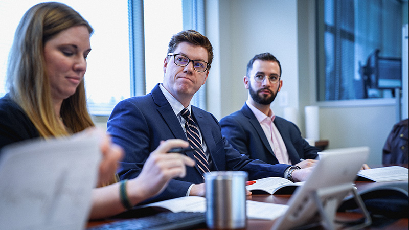 Two Business men with laptops in a meeting look at someone off screen