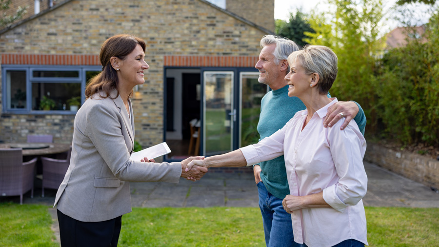 woman greeting couple in front of home