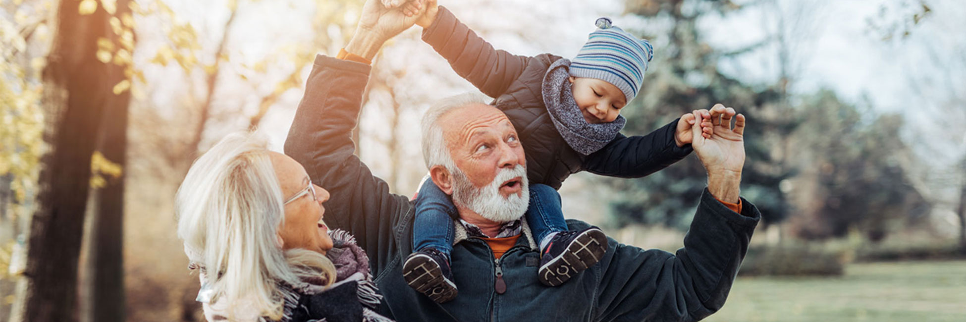 Grandparents playing with grandchild putting child on their shoulders.